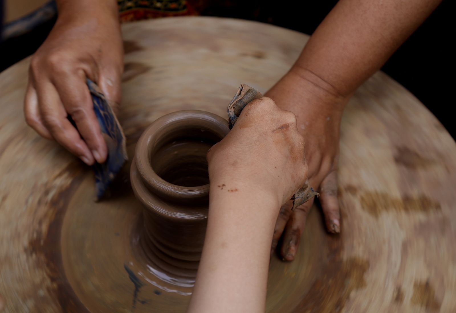 Hands shaping clay on a potter's wheel