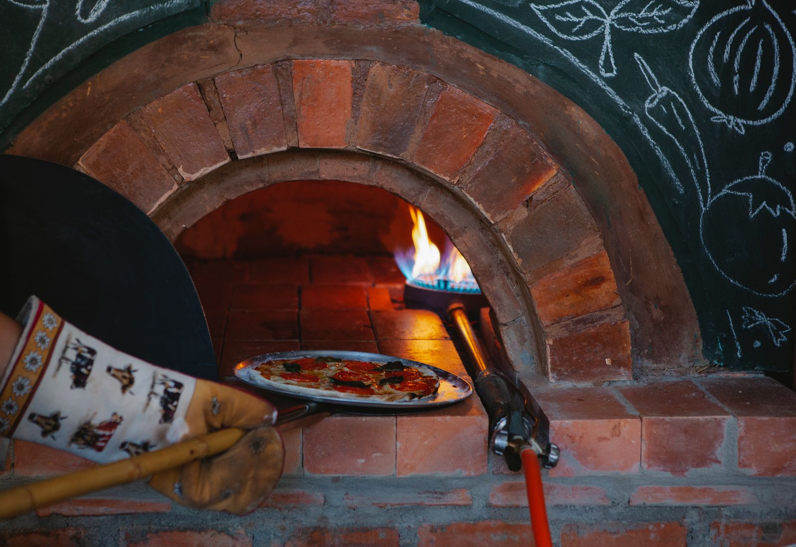 Chef sliding a pizza into the wood-fired oven